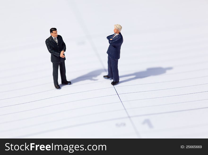 Two figures of businessmen standing on a calendar sheet and negotiate about a business. Two figures of businessmen standing on a calendar sheet and negotiate about a business