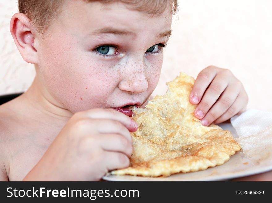 Closeup portrait of little boy eating meat pie named �cheburek�. Closeup portrait of little boy eating meat pie named �cheburek�