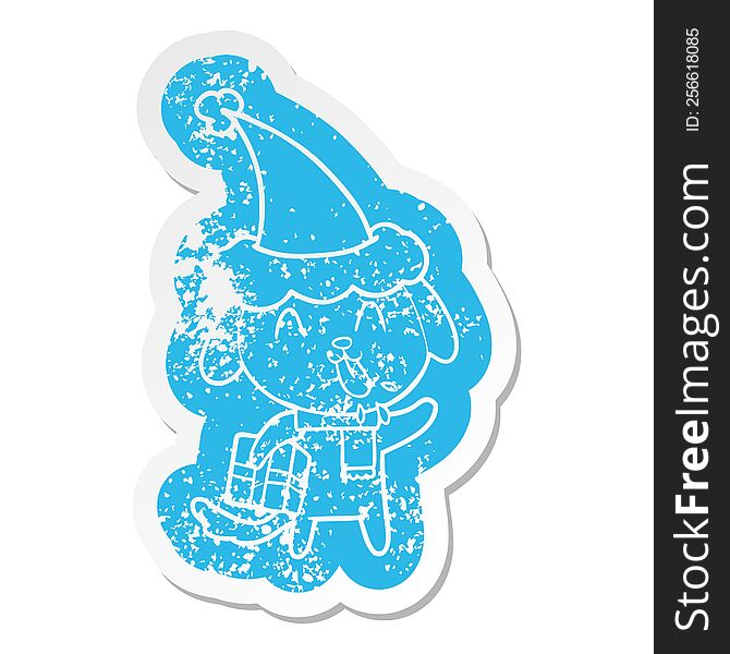cute quirky cartoon distressed sticker of a dog with christmas present wearing santa hat