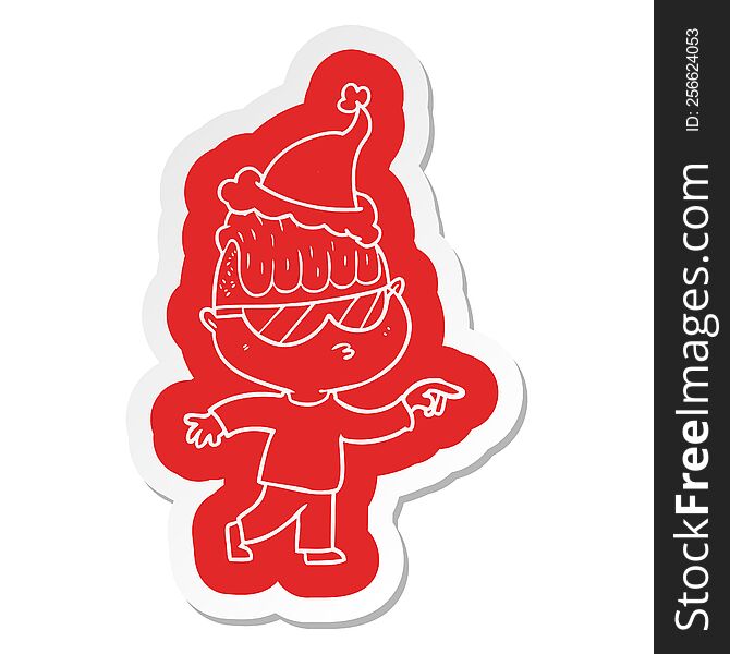 quirky cartoon  sticker of a boy wearing sunglasses pointing wearing santa hat