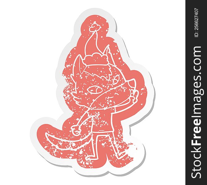 friendly quirky cartoon distressed sticker of a wolf giving peace sign wearing santa hat