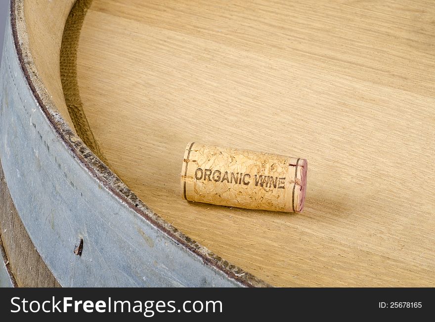 A cork labelled organic wine resting on top of a used wine barrel.