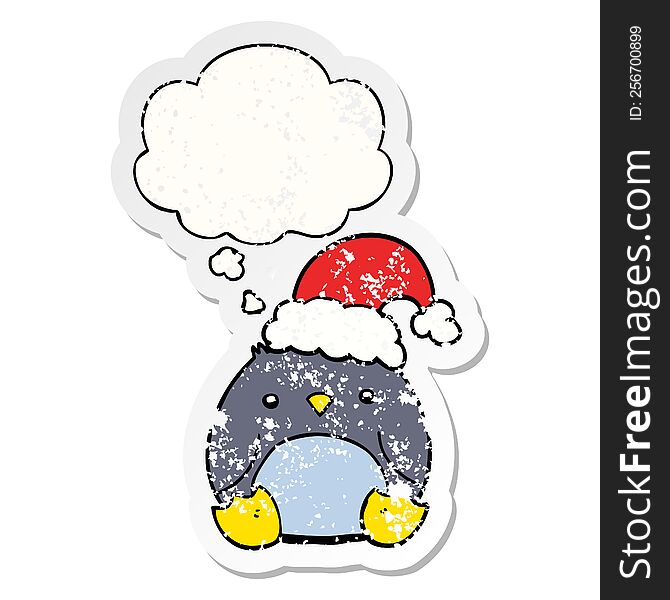 cute cartoon penguin wearing christmas hat with thought bubble as a distressed worn sticker