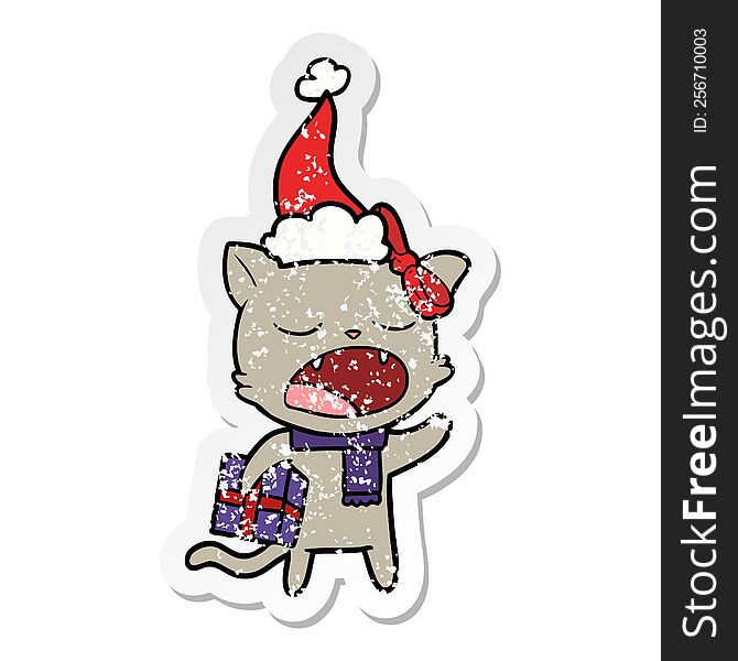 hand drawn distressed sticker cartoon of a cat with christmas present wearing santa hat