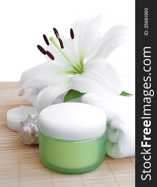 White lily, towel, candle, body cream on white background. White lily, towel, candle, body cream on white background