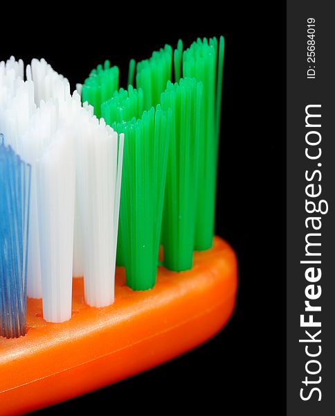 A close up of unused toothbrush with green, white and blue bristles on a black background. A close up of unused toothbrush with green, white and blue bristles on a black background