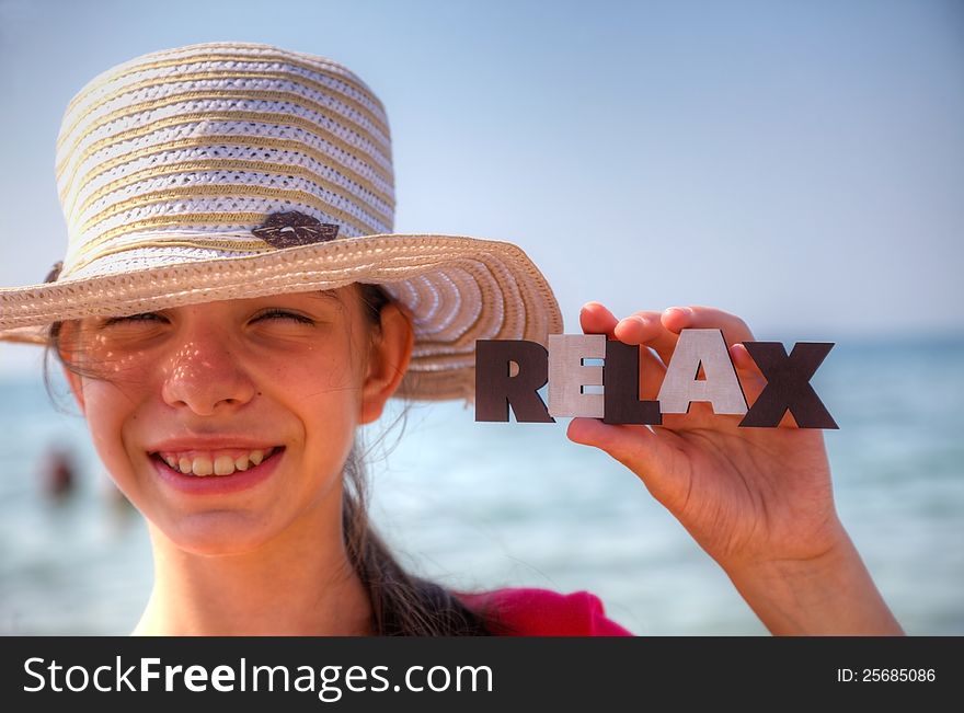 Teen girl at a beach holding word Relax