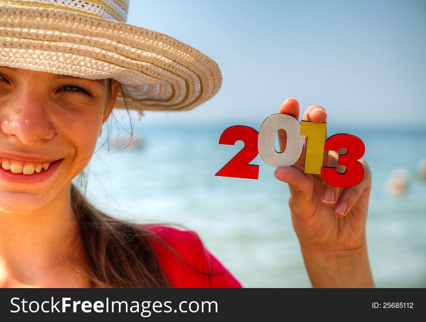 Teen girl at a beach holding wooden number '2013'. Teen girl at a beach holding wooden number '2013'