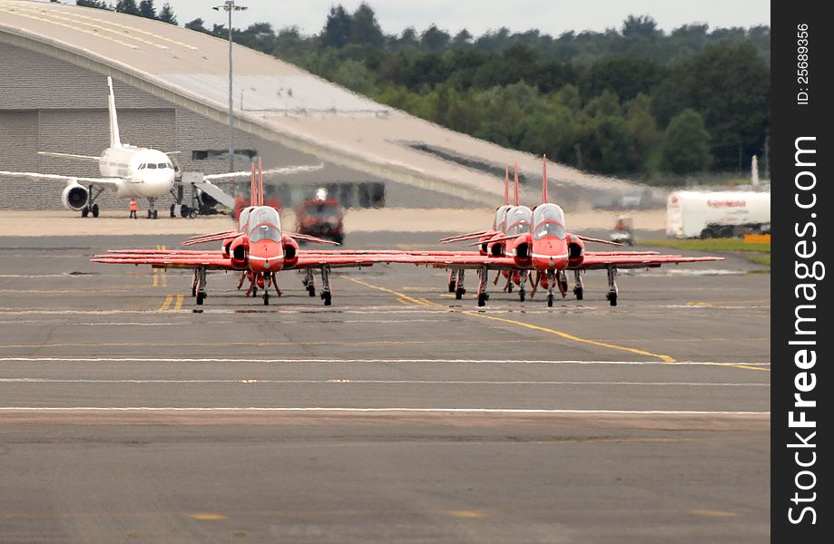 BAE Systems Hawk T1s of the RAF Red Arrows display team taxiing on the runway at Farnborough. England. Engine jet exhaust giving heat haze, with long lens compressed depth. BAE Systems Hawk T1s of the RAF Red Arrows display team taxiing on the runway at Farnborough. England. Engine jet exhaust giving heat haze, with long lens compressed depth.