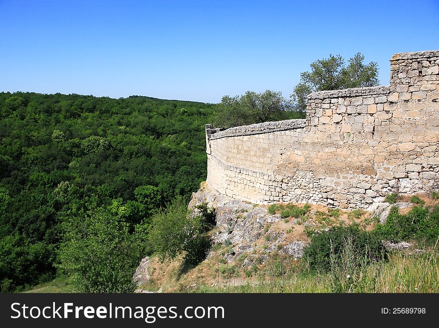 Stone wall of the ancient fortress on mountain above green valley. Stone wall of the ancient fortress on mountain above green valley