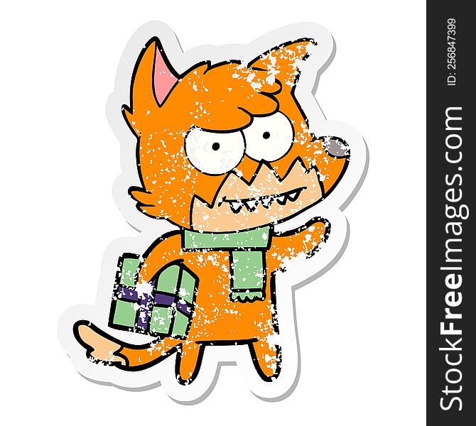 distressed sticker of a cartoon grinning fox with christmas present