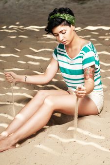 Girl With Tattoo On The Beach Pours Sand Stock Photography