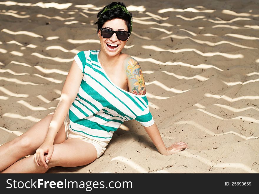 Pretty female model with tattoo and in sunglasses on the beach in the shade. Pretty female model with tattoo and in sunglasses on the beach in the shade