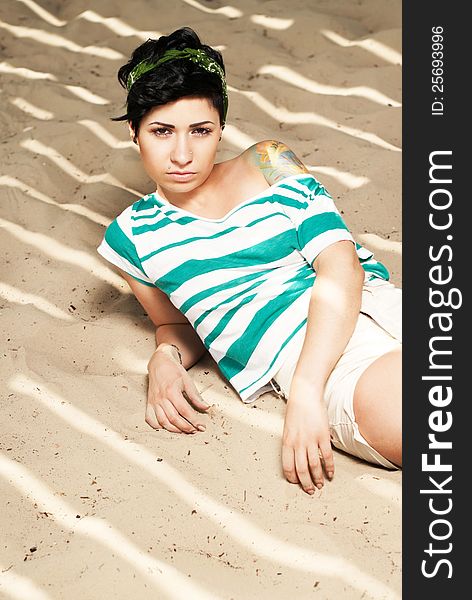 Pretty female model with tattoo on the beach in the shade. Pretty female model with tattoo on the beach in the shade