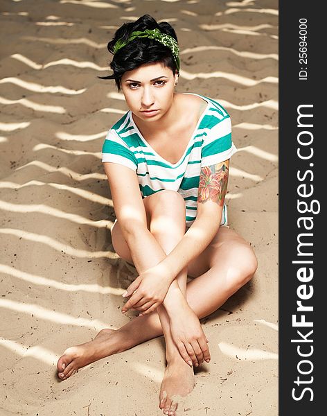 Pretty female model with tattoo on the beach in the shade. Pretty female model with tattoo on the beach in the shade