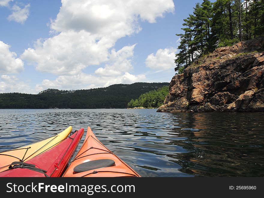 A group of three kayaks nose toward the wilderness shores of a peaceful lake. A group of three kayaks nose toward the wilderness shores of a peaceful lake.