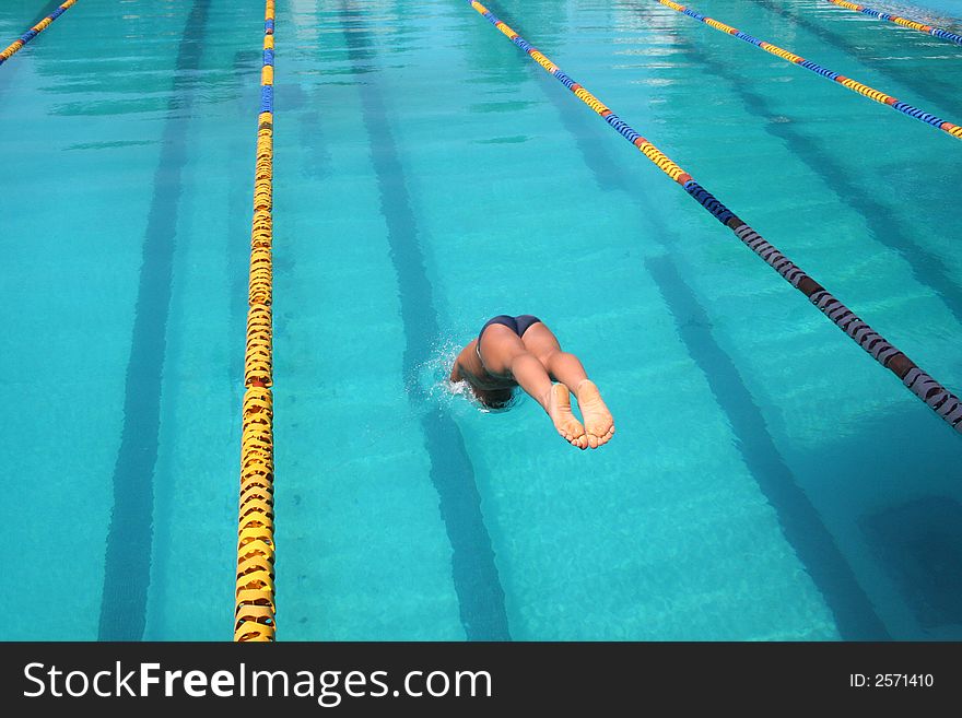 A young boy diving into the pool for a race at a local state championship. A young boy diving into the pool for a race at a local state championship