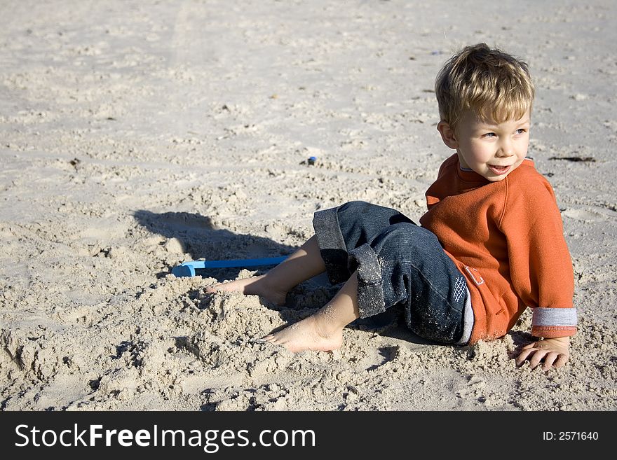 Barefoot toddler sitting on the sand. Barefoot toddler sitting on the sand