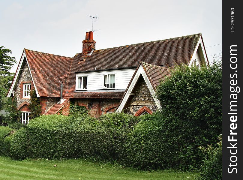 English Brick and Flint House surrounded by a Shrub Hedge. English Brick and Flint House surrounded by a Shrub Hedge