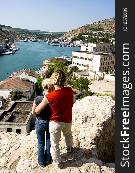 The embraced guy and the girl on a slope of mountain above a sea bay