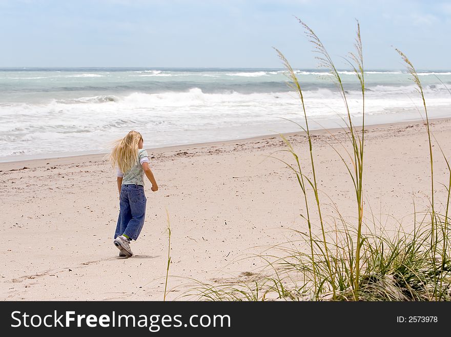 Young girl walking on the beach with Sea Oats in foreground. Young girl walking on the beach with Sea Oats in foreground