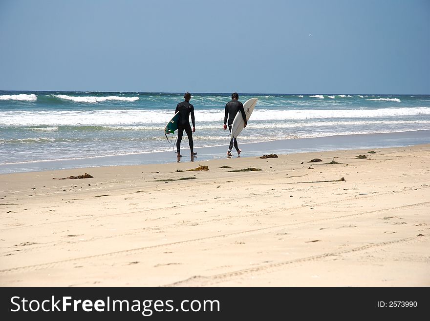 Two surfer walking by the beach