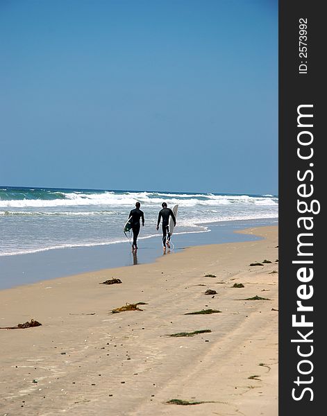 Two surfer walking by the beach