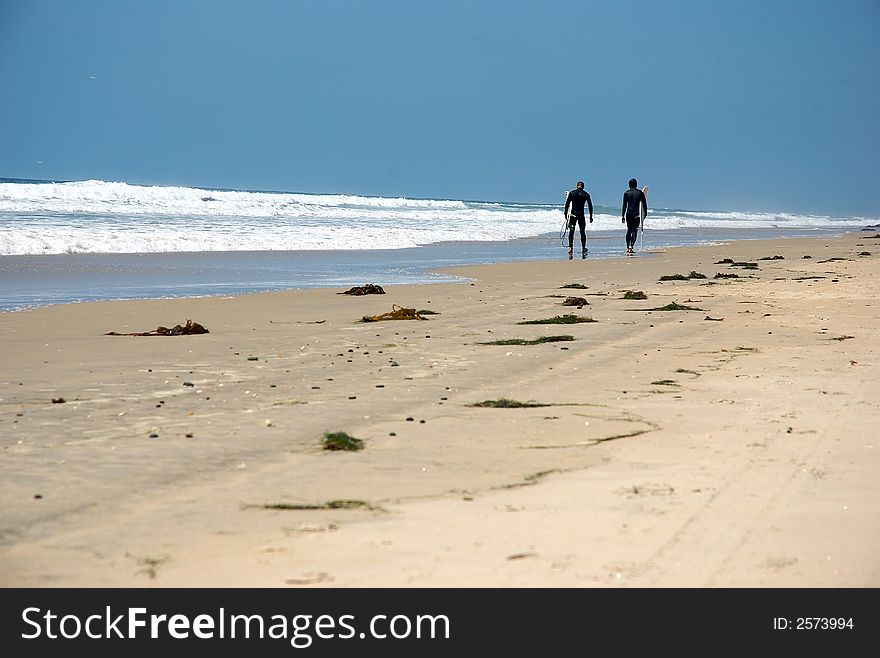 Two surfer walking by the beach