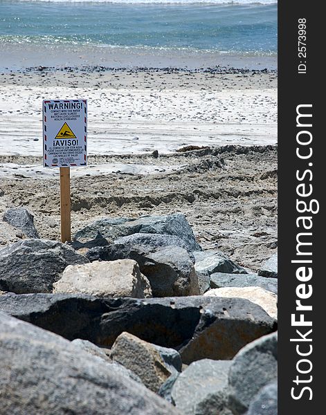 A sign on a rocky beach with ocean background. A sign on a rocky beach with ocean background