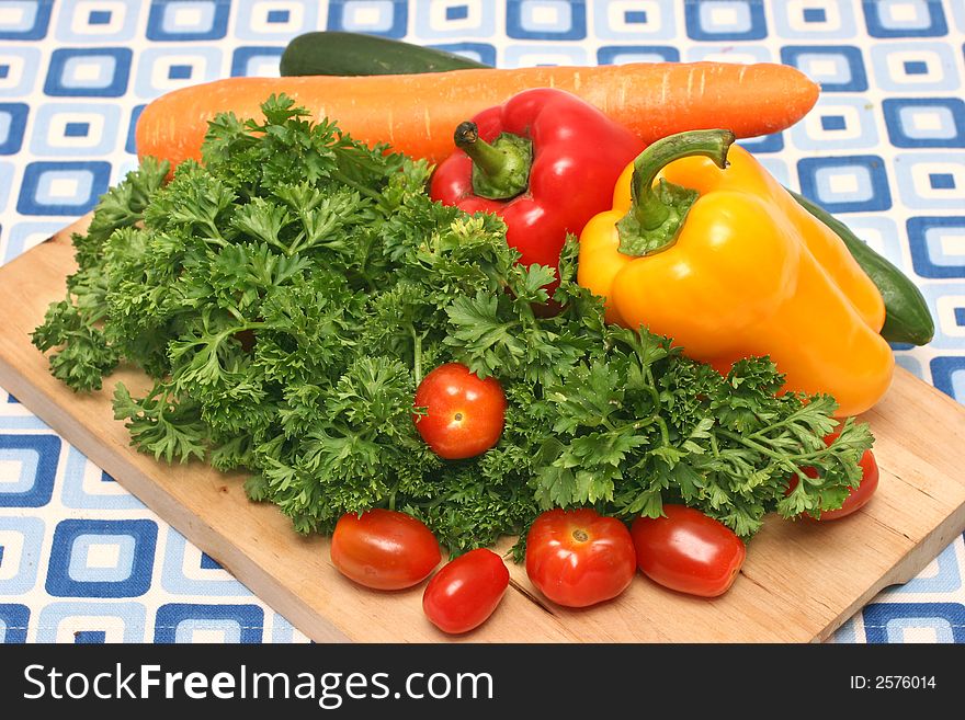 Parsley, cherry tomatoes, capsicums, carrot and cucumber on wooden board. Parsley, cherry tomatoes, capsicums, carrot and cucumber on wooden board