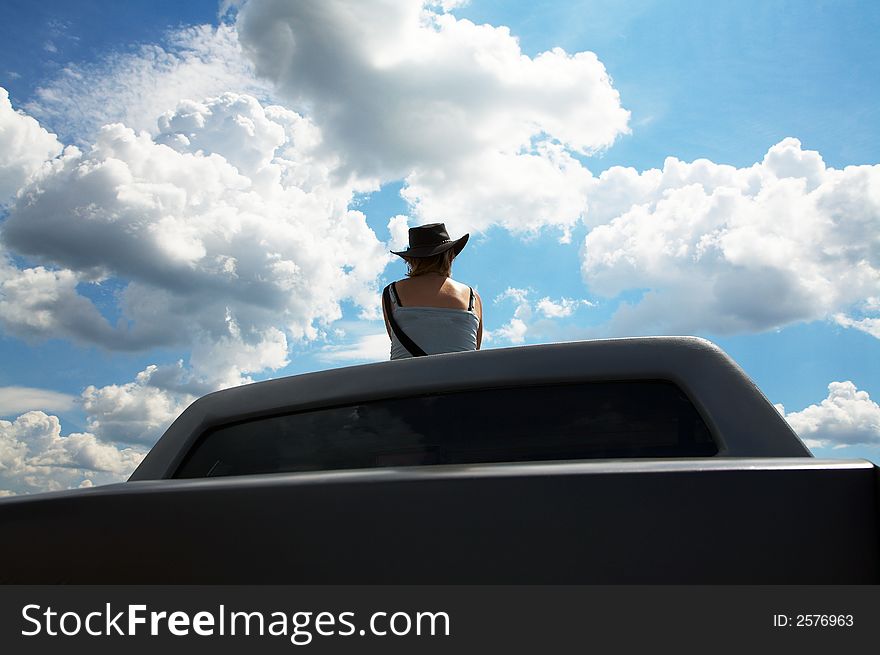 The girl in a cowboy's hat on a roof of the car