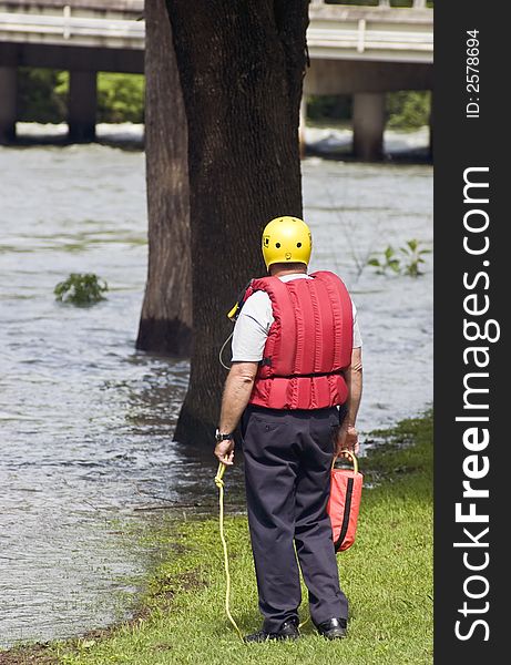 A member of an emergency team standy ready to assist his teammates from the banks of a flooded river. A member of an emergency team standy ready to assist his teammates from the banks of a flooded river.