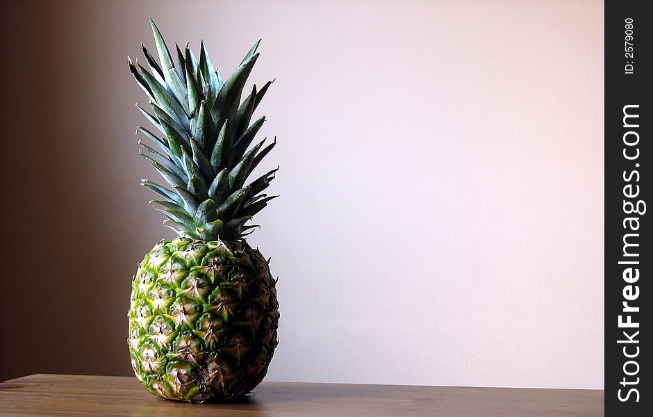 Pineapple with peach background on a table.