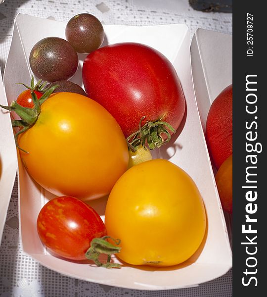 In a small paper tray tomatoes are on display for sale. In a small paper tray tomatoes are on display for sale