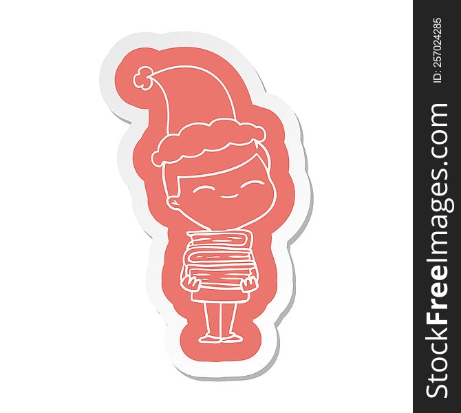 quirky cartoon  sticker of a smiling boy with stack of books wearing santa hat