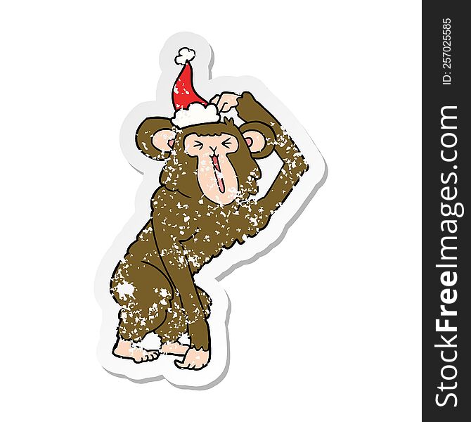 hand drawn distressed sticker cartoon of a chimp scratching head wearing santa hat