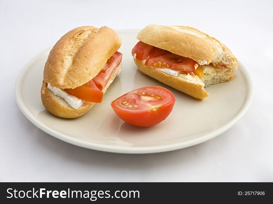 Buns on a plate filled with cheese and tomatoes, two and a half rolls stuffed tomato on a plate on a white background. Buns on a plate filled with cheese and tomatoes, two and a half rolls stuffed tomato on a plate on a white background