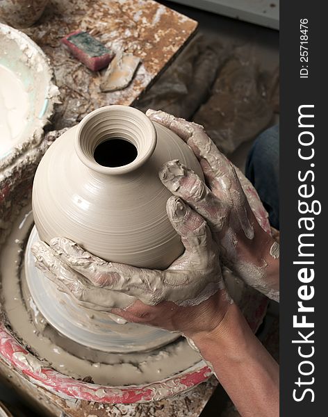 Hands of a potter, creating an earthen jar on the circle