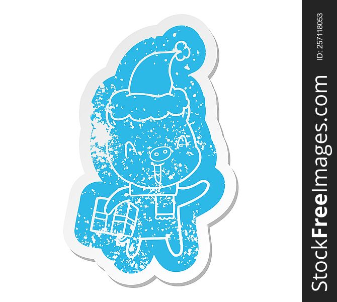 Happy Cartoon Distressed Sticker Of A Pig With Xmas Present Wearing Santa Hat