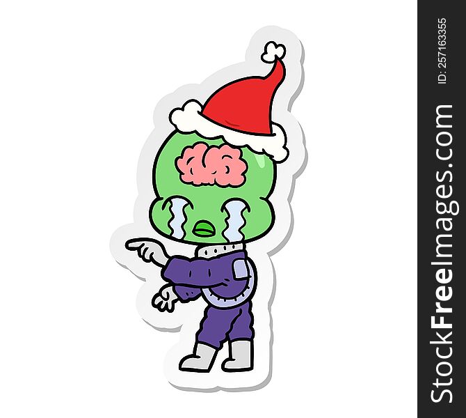 Sticker Cartoon Of A Big Brain Alien Crying And Pointing Wearing Santa Hat