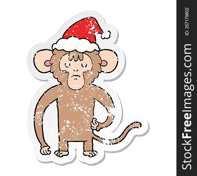 hand drawn distressed sticker cartoon of a monkey scratching wearing santa hat