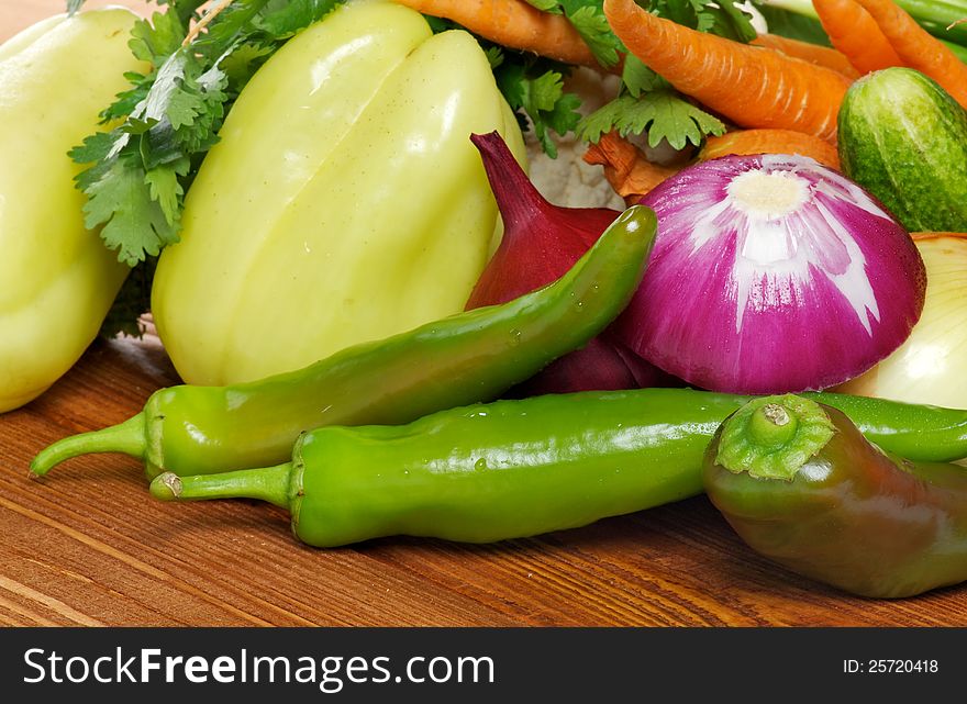 Vegetable Set of Green Bell Pepper, Chili peppers, Red Onion, Carrot and greens closeup on wooden background