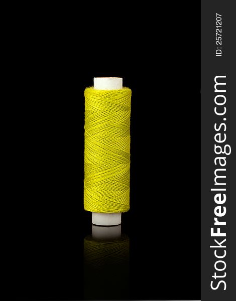 Yellow spindle of yarn isolated over black background