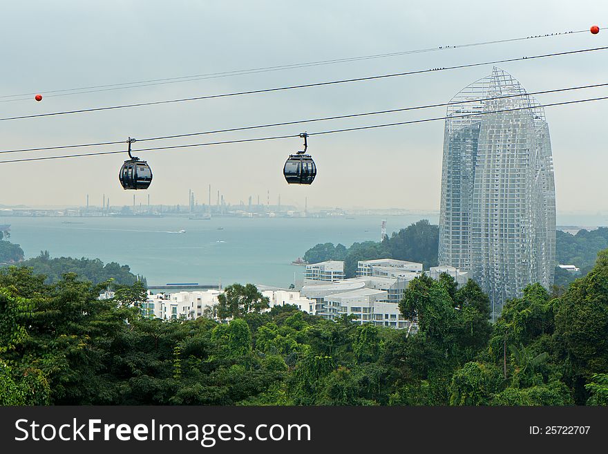 View of two cable cars passing by a skyscraper and a forest. View of two cable cars passing by a skyscraper and a forest.