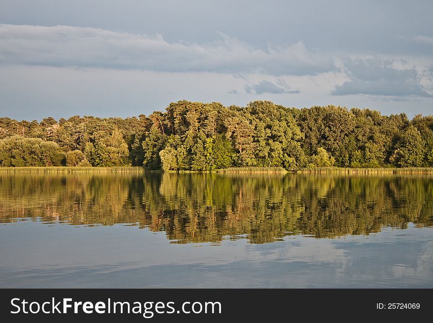 Sky and green trees in nature over lake with reflections. Sky and green trees in nature over lake with reflections