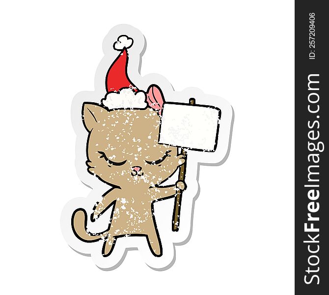 cute hand drawn distressed sticker cartoon of a cat with sign wearing santa hat