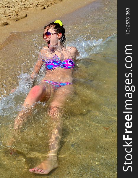 Image of a girl on the beach with a wave splashing over her