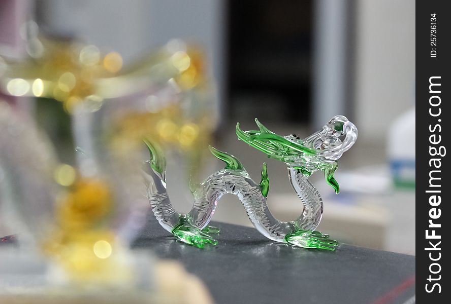 Close up of glass dragon. Focus from soft to sharp emphasizing the dragons head and green skin. Close up of glass dragon. Focus from soft to sharp emphasizing the dragons head and green skin.