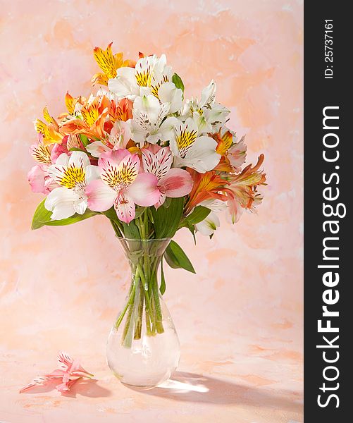Bouquet of Alstroemeria in a transparent glass vase on abstract background
