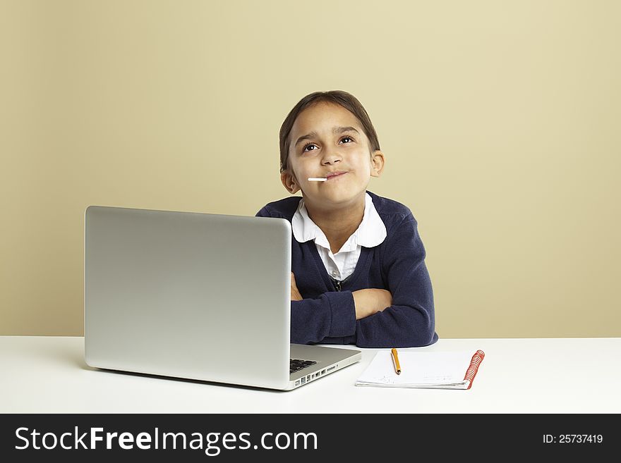 Young girl using laptop on white desk with homework